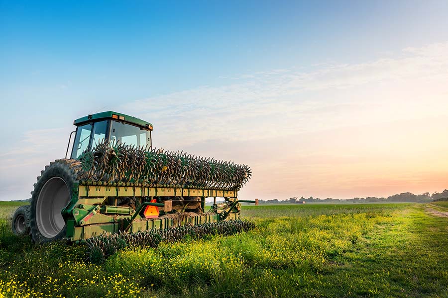 Farm Insurance - View of Modern Tractor Parked in Field of Crops