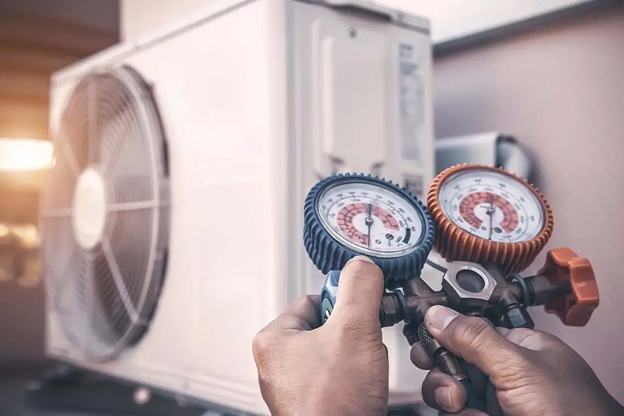 HVAC Contractor Insurance - HVAC Mechanic Using Pressure Gauge Equipment for Home Air Conditioner After Maintenance and Checking Outdoor Air Compressor Unit